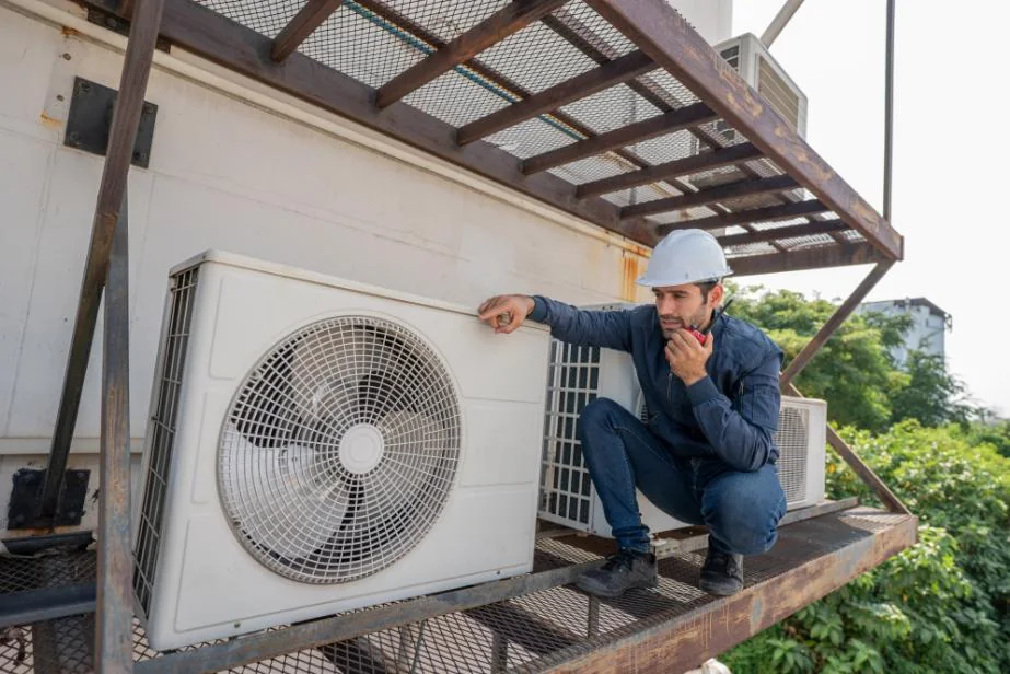 Generic service model inspecting an outdoor air-conditioning condenser on an elevated platform