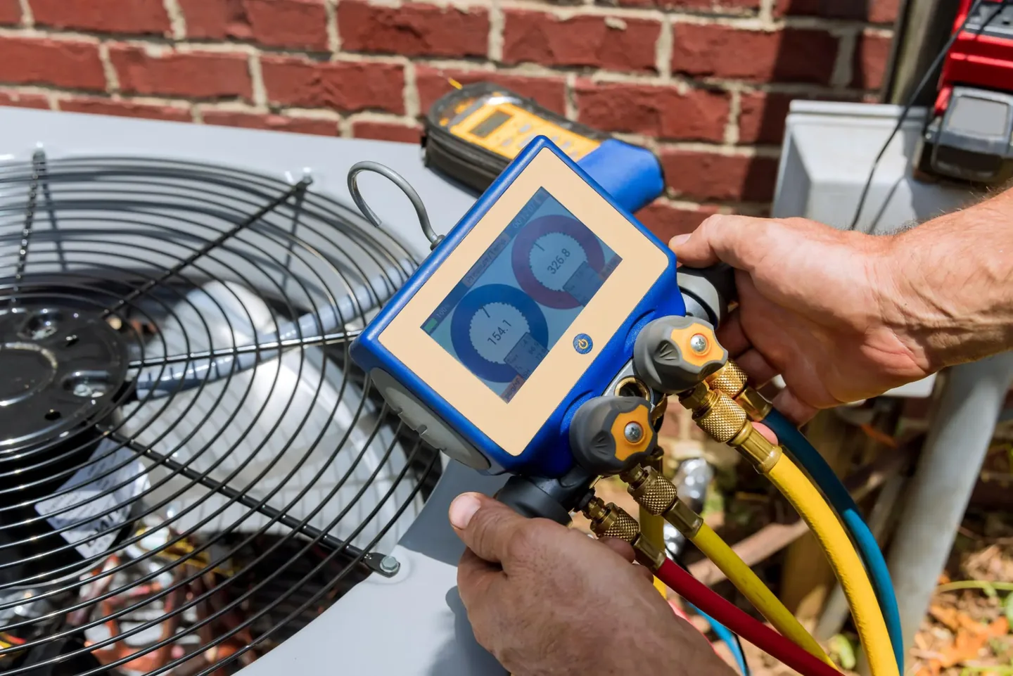 Close-up of a generic service model using a digital HVAC gauge and service hoses
