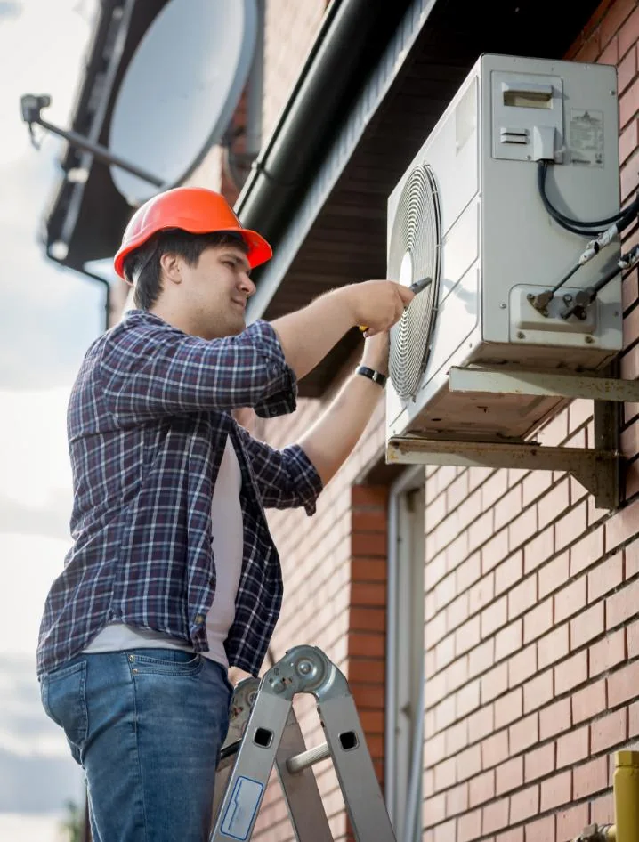 Generic service model working on an outdoor HVAC unit beside a brick wall